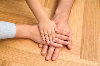 Photo of Happy family holding hands on wooden background, closeup