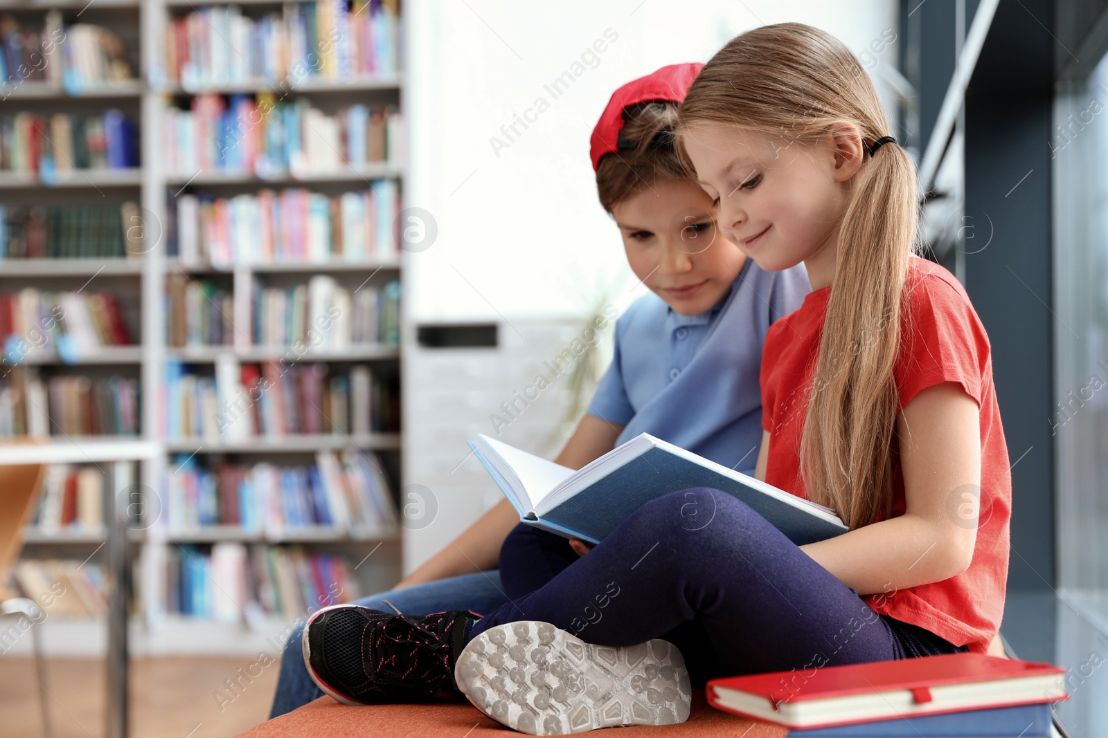 Photo of Happy little children reading book in library