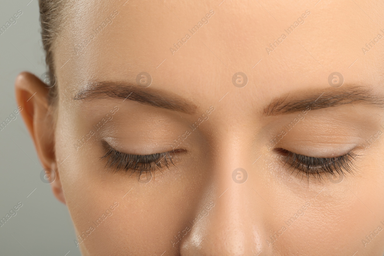 Photo of Woman with beautiful natural eyelashes on grey background, closeup