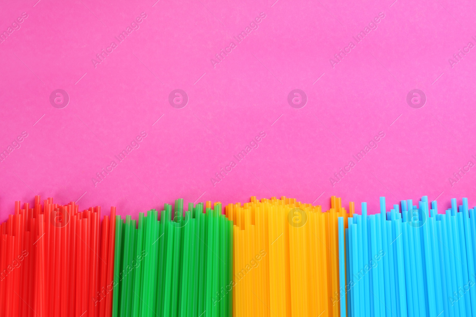 Photo of Colorful plastic drinking straws on pink background, flat lay. Space for text