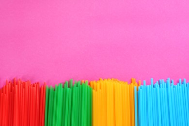 Colorful plastic drinking straws on pink background, flat lay. Space for text