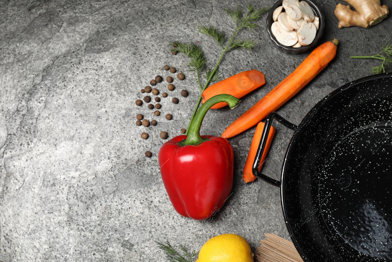 Photo of Empty iron wok and raw ingredients on grey table, flat lay. Space for text