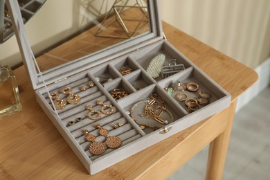 Elegant jewelry box with beautiful bijouterie and stylish accessories on wooden table in room