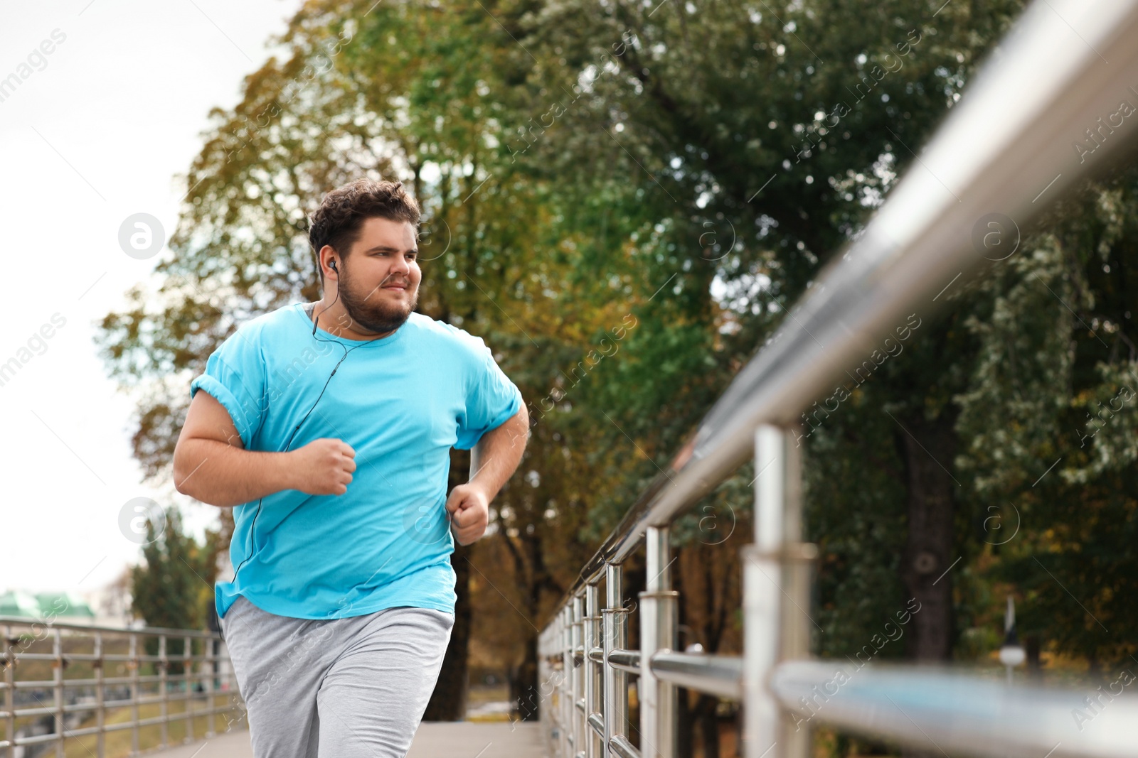 Photo of Young overweight man running outdoors. Fitness lifestyle