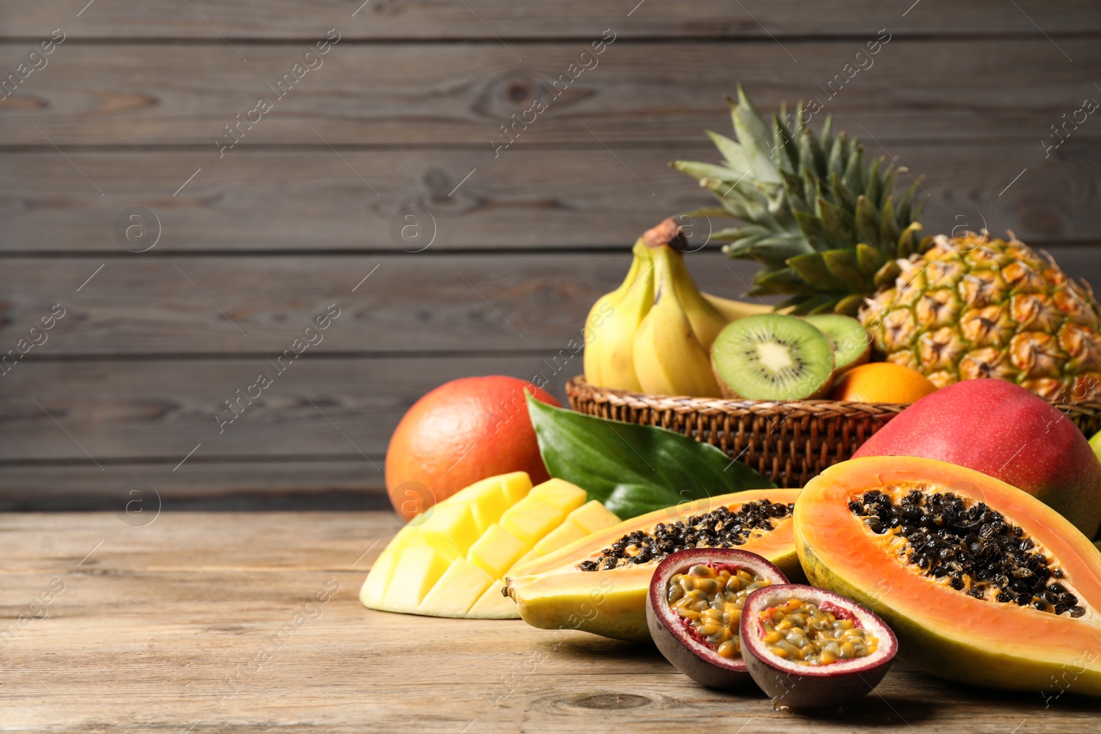 Photo of Fresh ripe papaya and other fruits on wooden table. Space for text