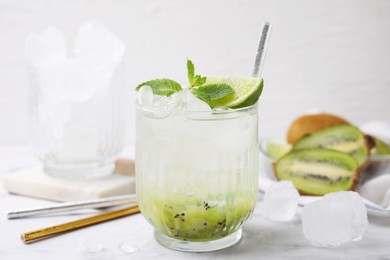 Photo of Glass of refreshing drink with kiwi, lime and mint on white table, closeup