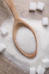 Photo of Different types of white sugar and spoon on wooden table, top view