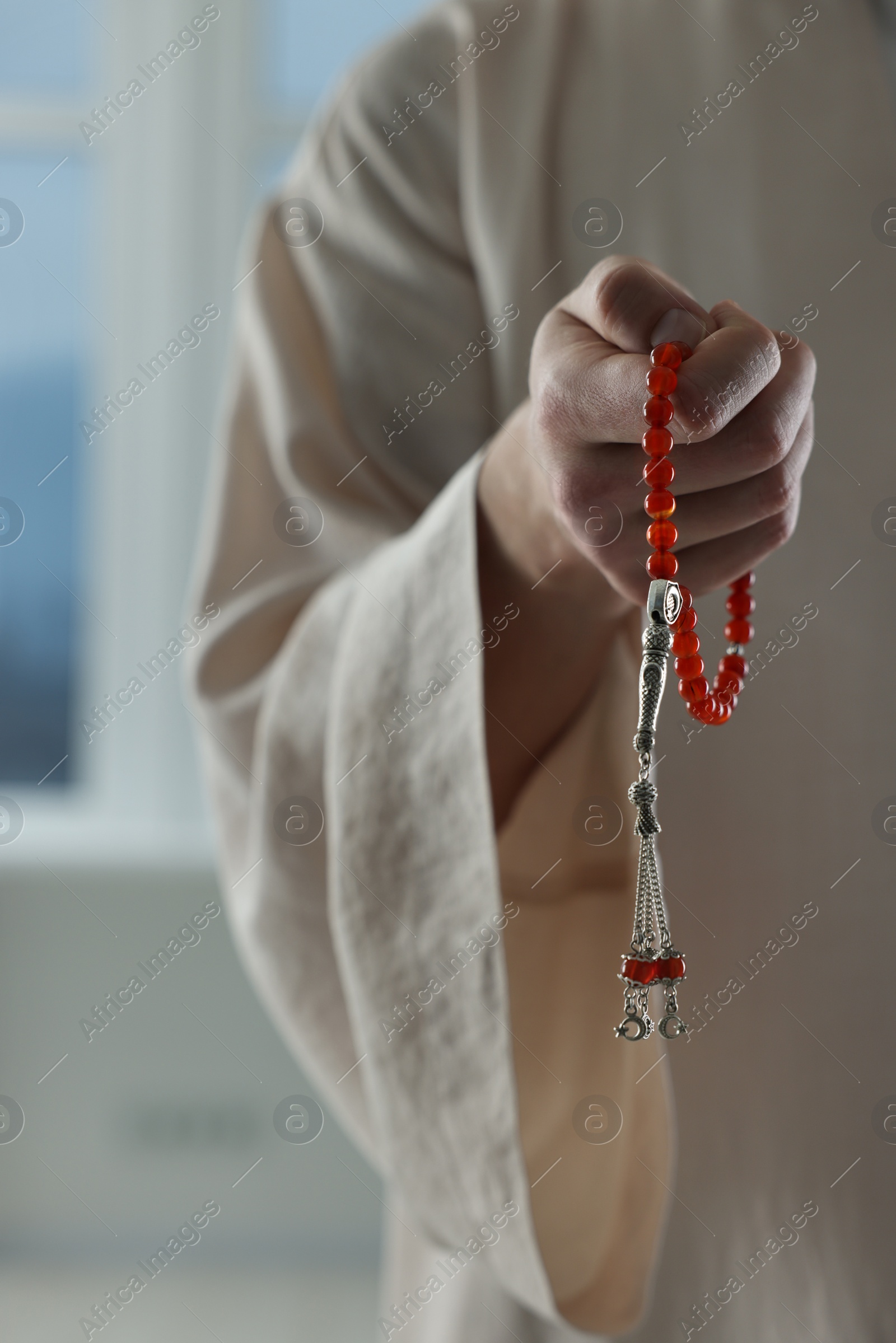 Photo of Muslim man with misbaha near window indoors, closeup