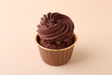 Delicious chocolate cupcake on beige background, closeup