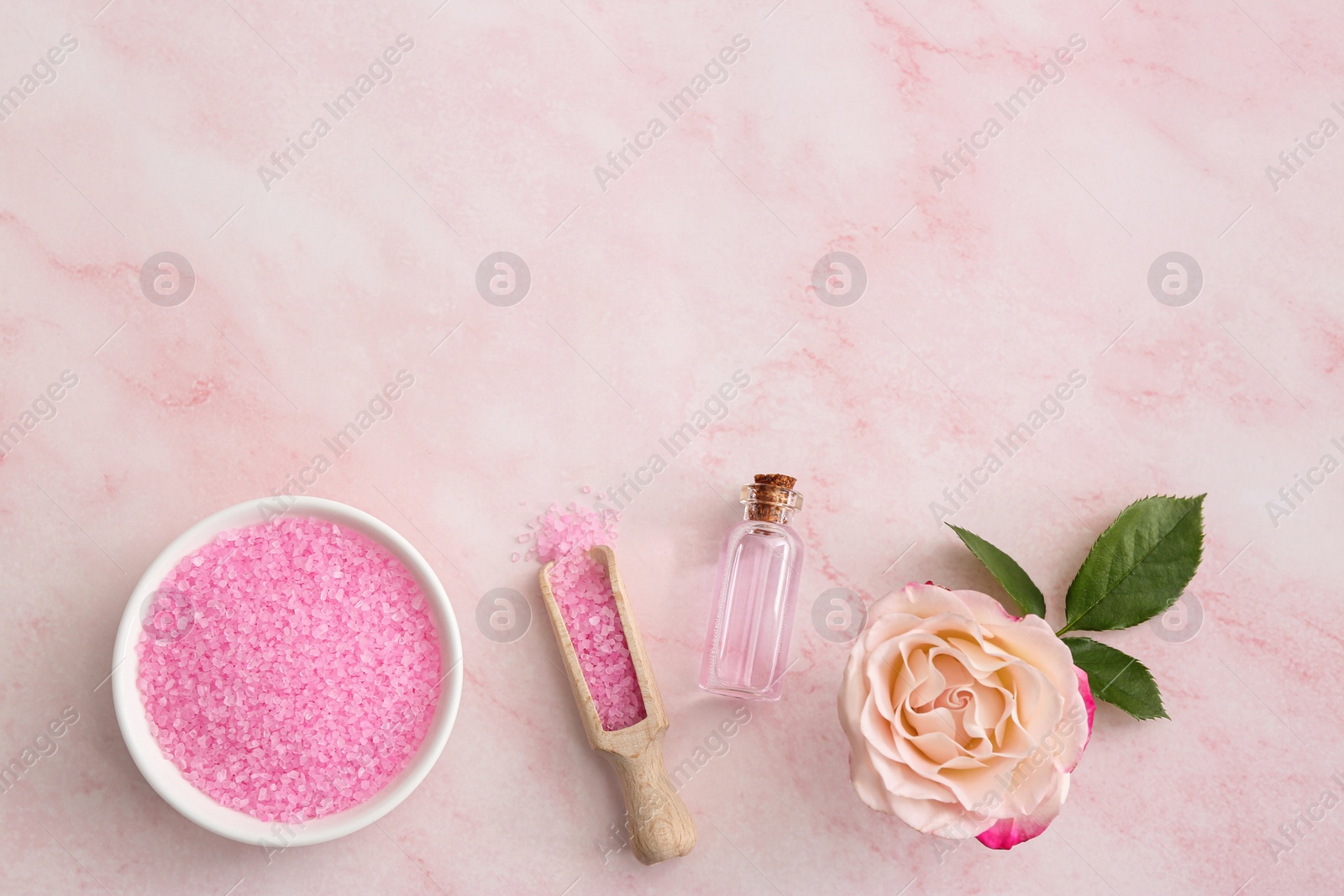 Photo of Bowl and scoop with sea salt, beautiful rose on pink marble table, flat lay. Space for text