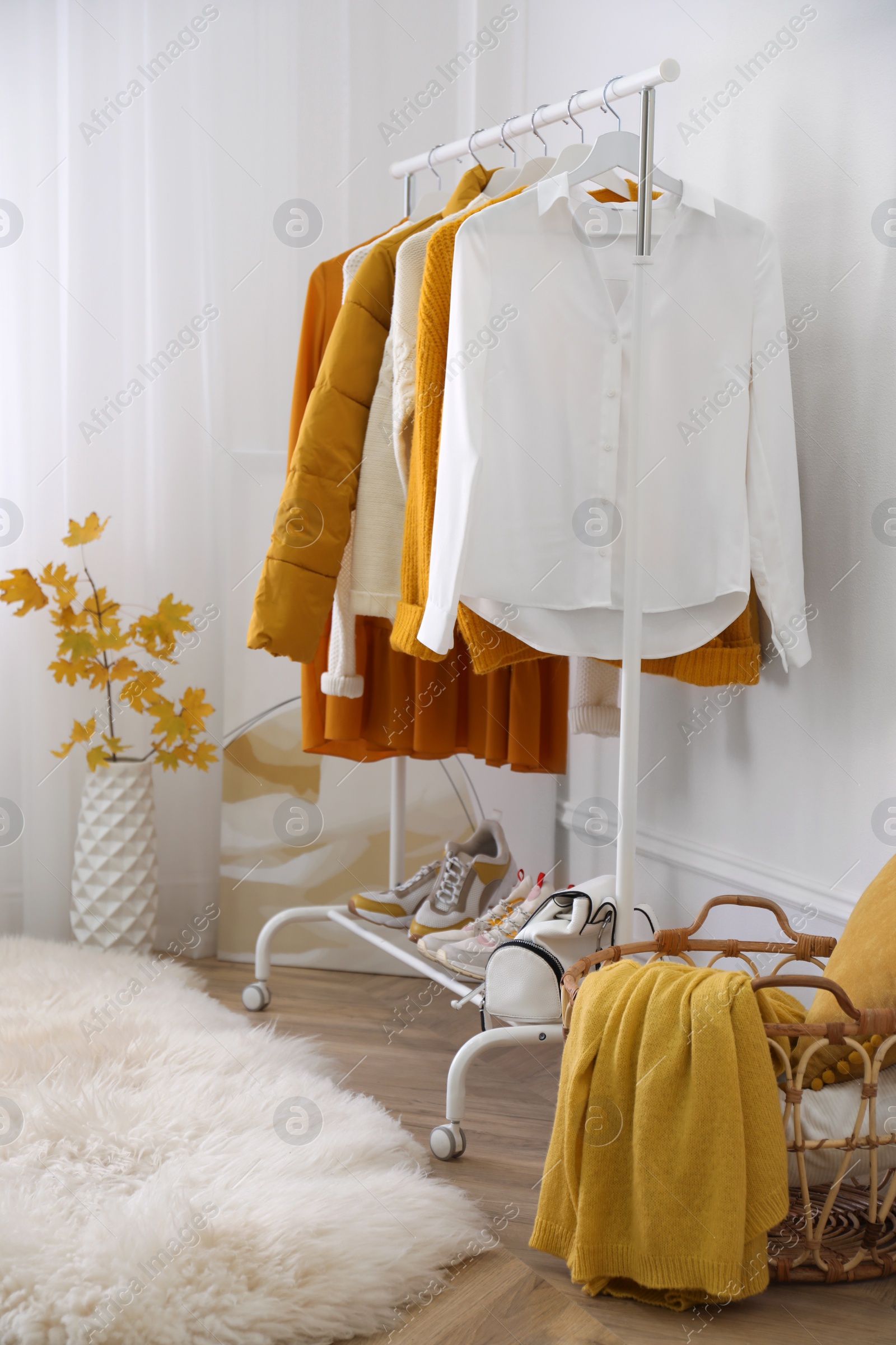 Photo of Rack with stylish warm clothes, shoes and accessories in modern dressing room