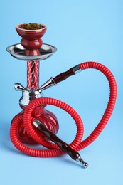 Photo of Modern red hookah on light blue background