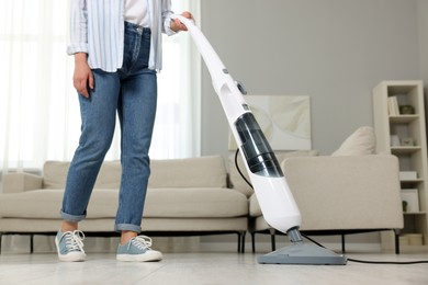 Photo of Woman cleaning floor with steam mop at home, closeup