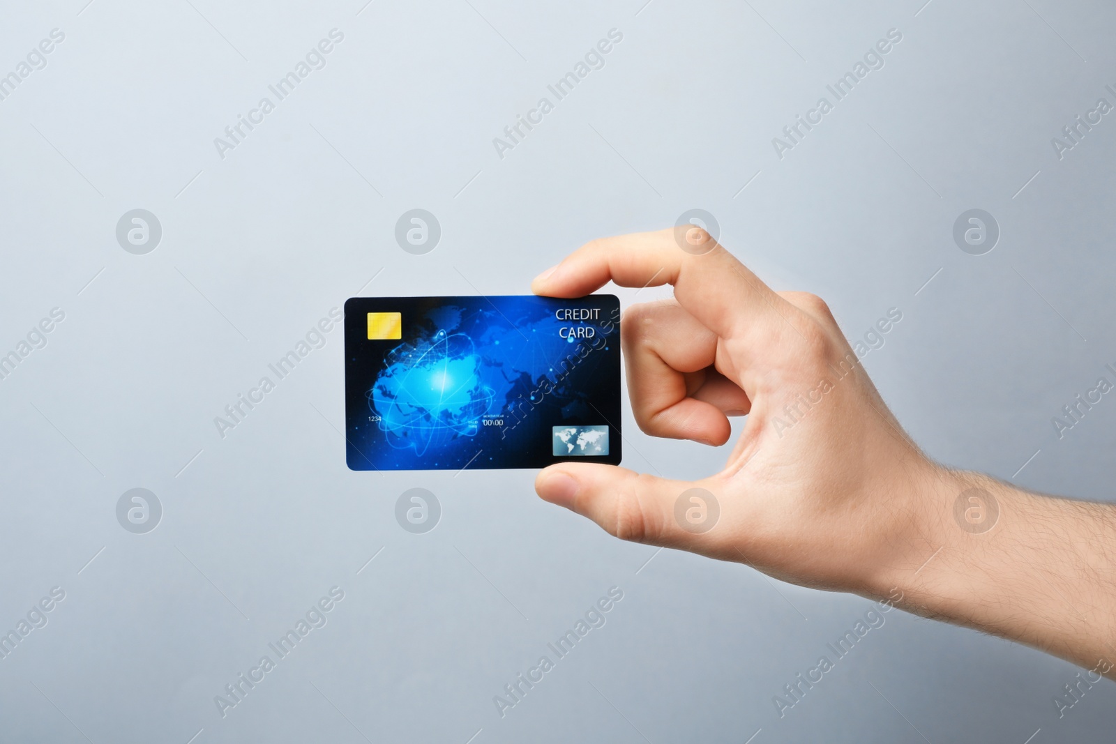 Photo of Young man holding credit card on grey background
