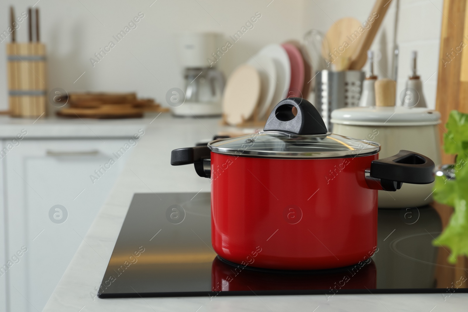 Photo of Red pot on electric stove in kitchen. Cooking utensil