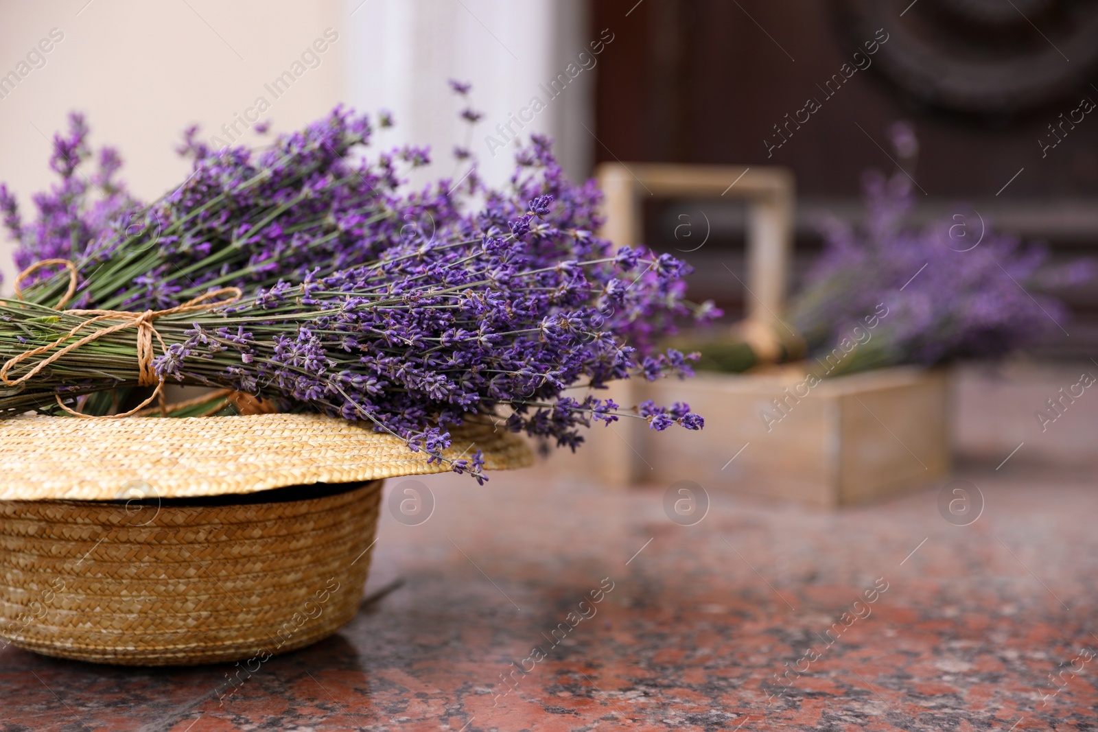 Photo of Beautiful lavender flowers and straw hat on marble tiles outdoors