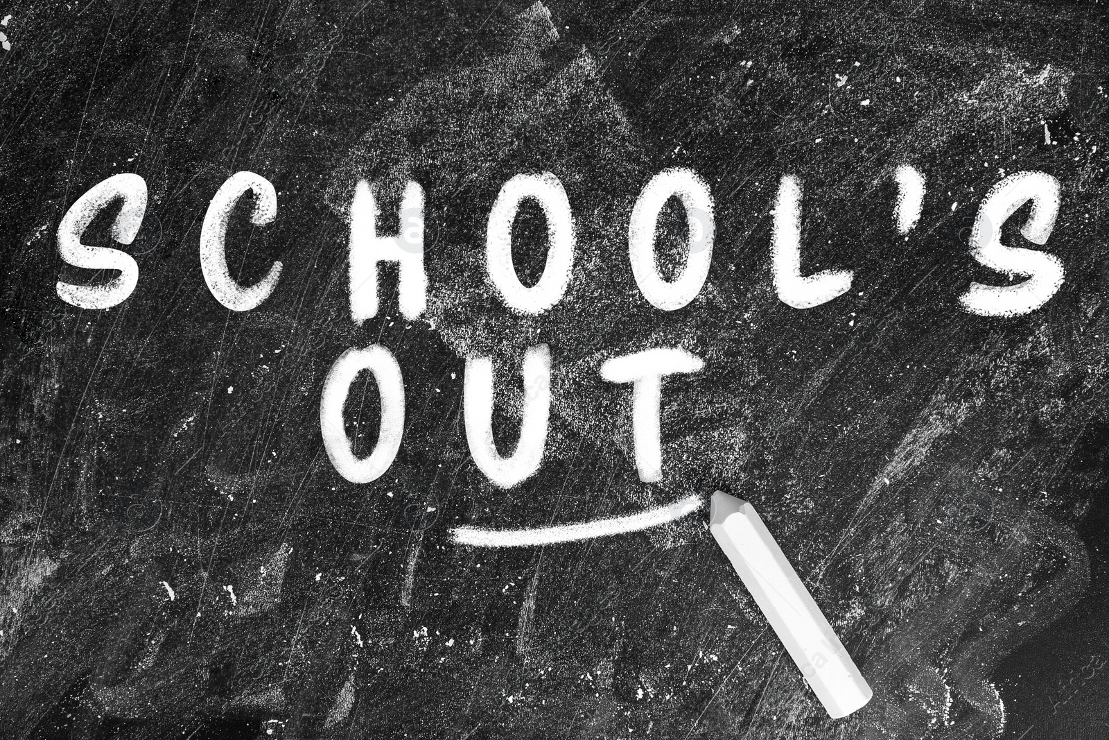 Image of Piece of chalk and text SCHOOL'S OUT written on blackboard, top view