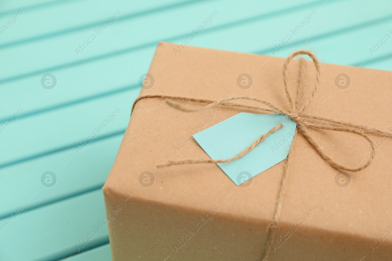 Photo of Parcel with tag on wooden background. Space for text