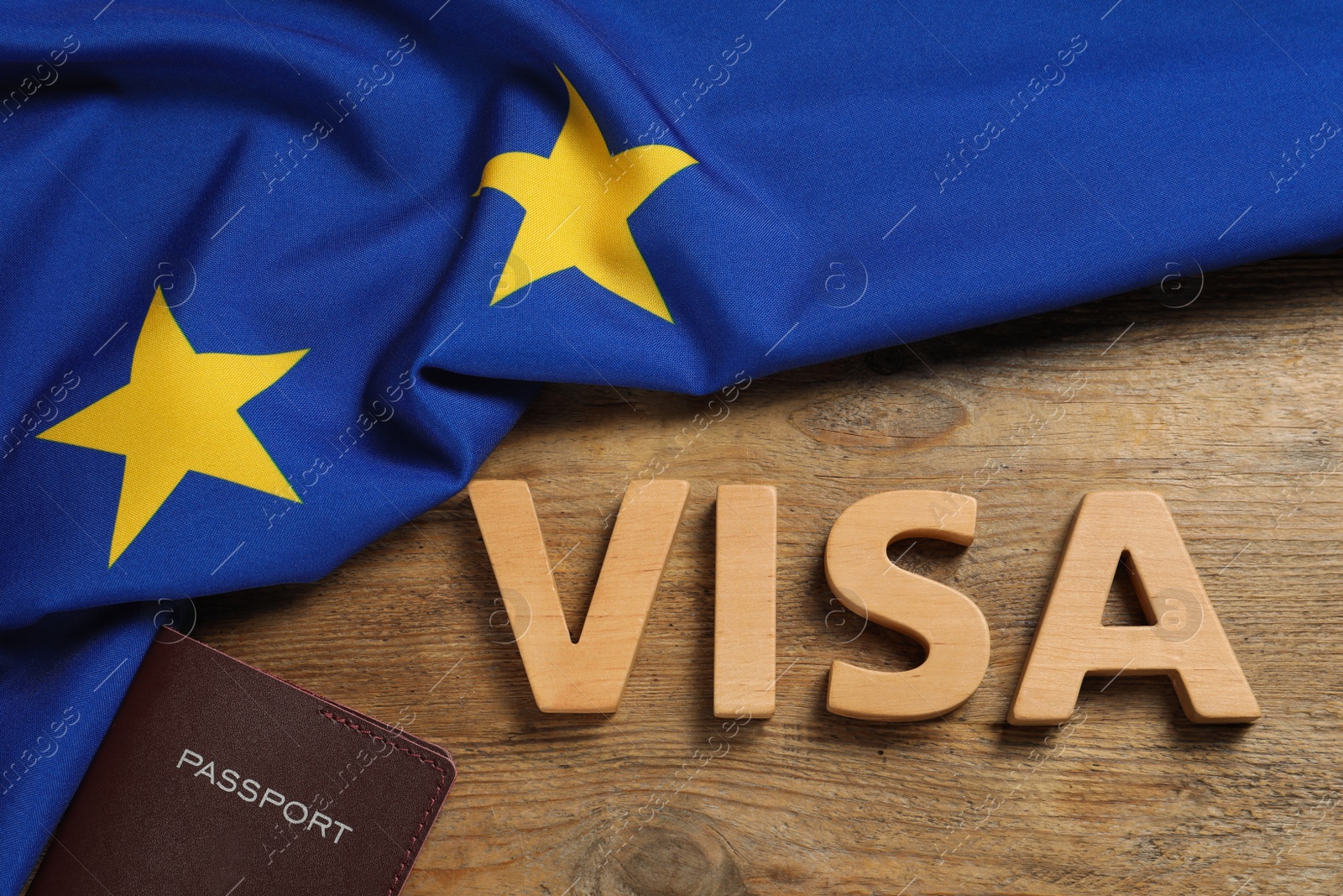 Photo of Word Visa made of wooden letters, passport and European Union flag on table, flat lay