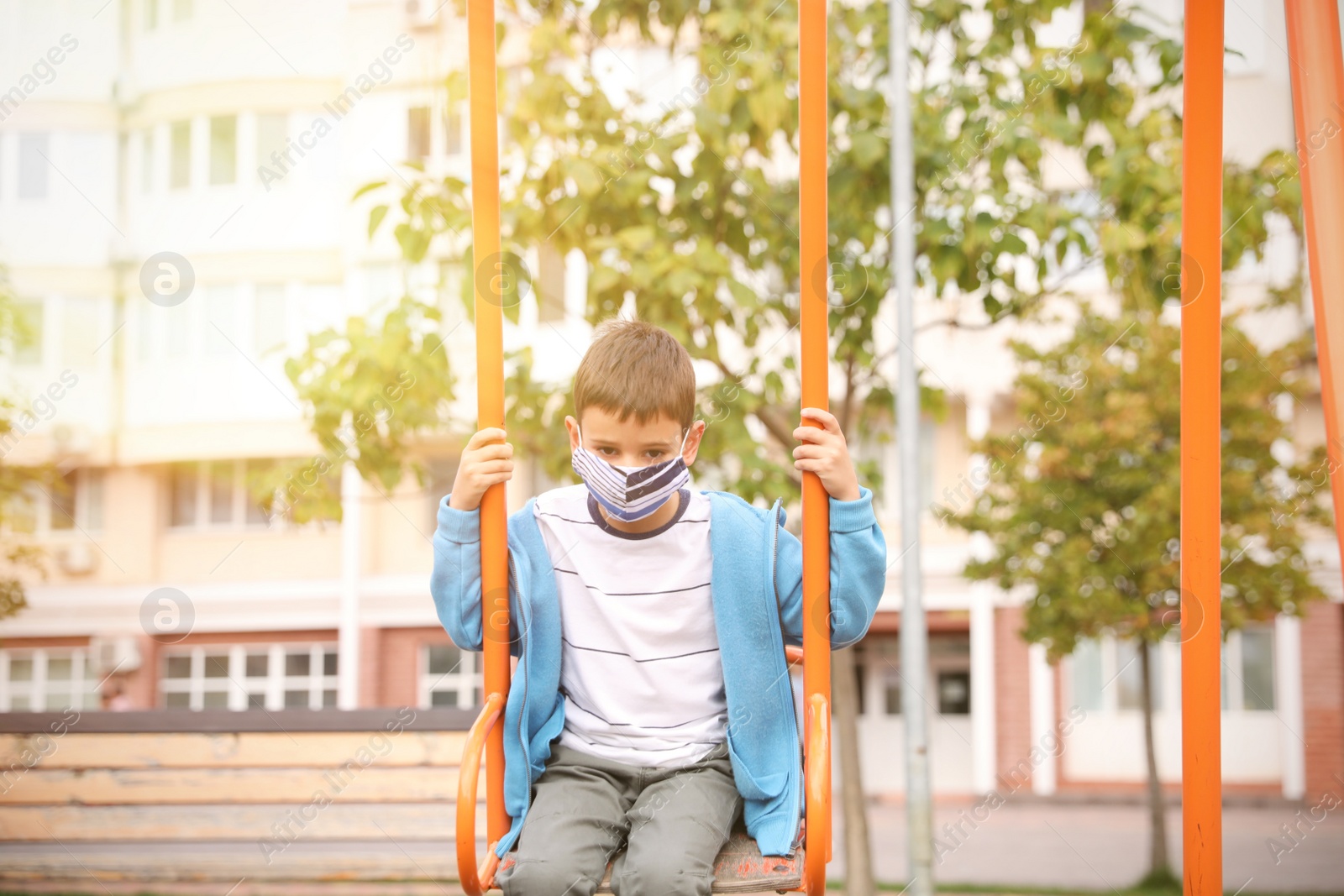 Photo of Little boy with medical face mask on playground during covid-19 quarantine