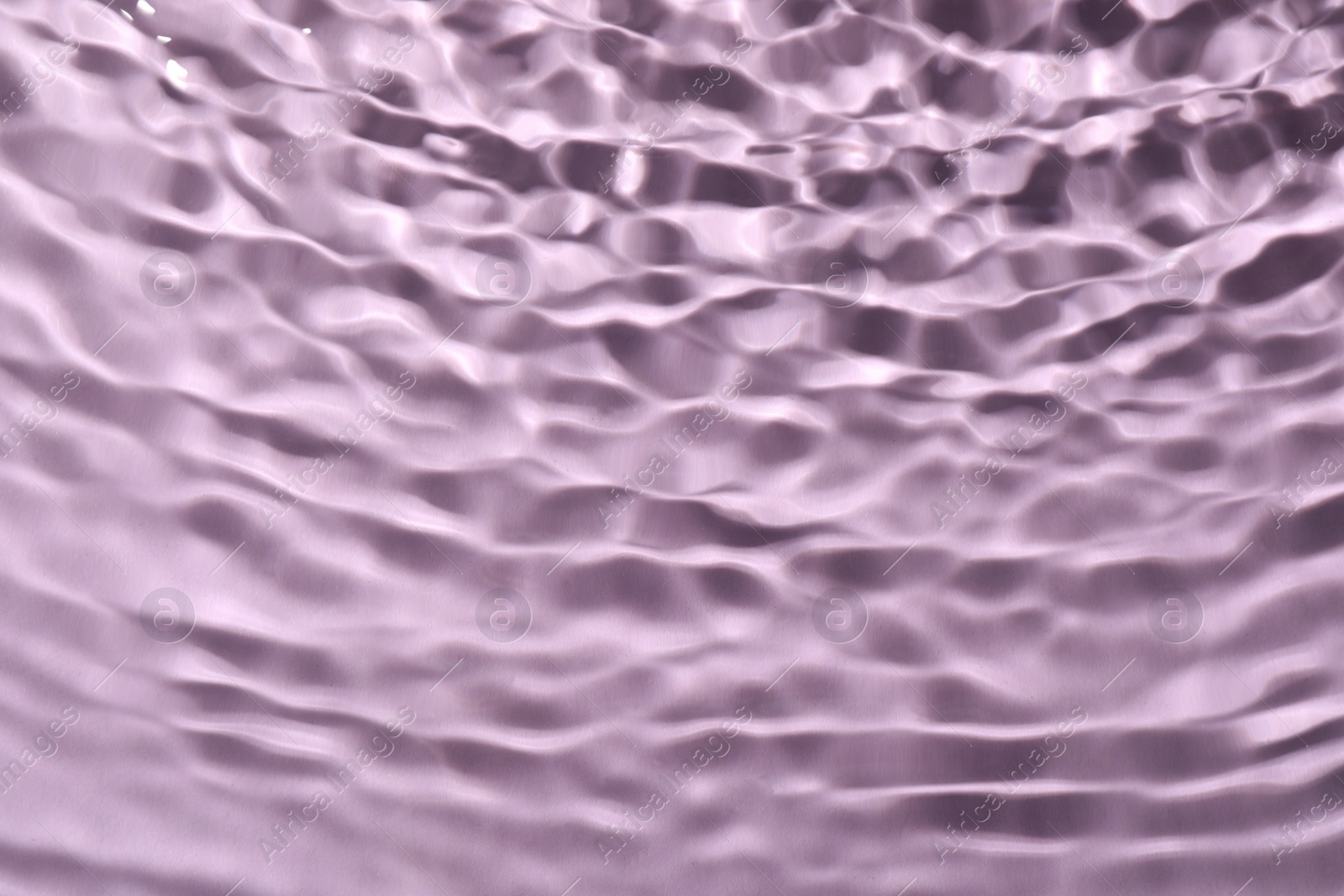 Photo of Closeup view of water with rippled surface on violet background