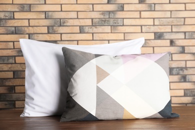 Soft decorative pillows on table against brick wall background