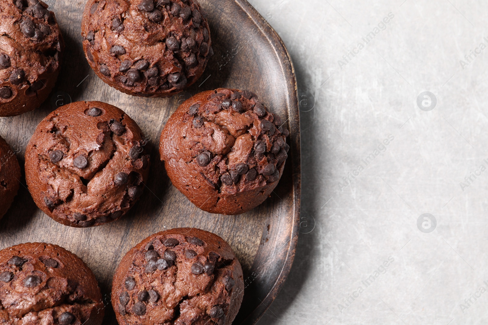 Photo of Tasty chocolate muffins on grey table, top view. Space for text