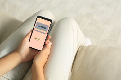 Image of Cashback. Woman holding smartphone indoors, closeup. Illustration of credit card and percent signs on device screen