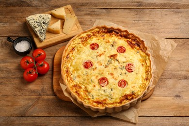 Photo of Delicious quiche with cheese and tomatoes on wooden table, above view