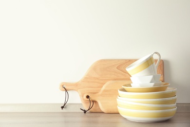 Set of dishware on table against light background with space for text. Interior element
