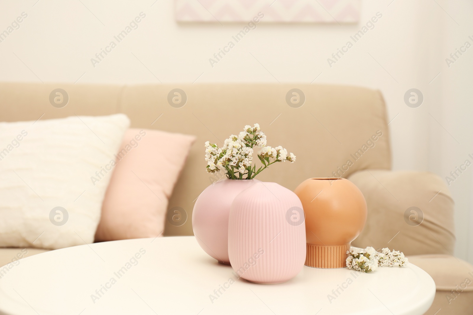 Photo of Beautiful ceramic vases and flowers on table in living room