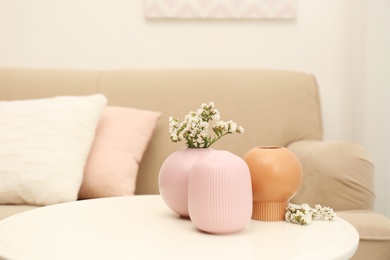 Photo of Beautiful ceramic vases and flowers on table in living room