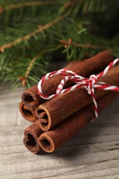 Cinnamon sticks and fir branches on wooden table, closeup