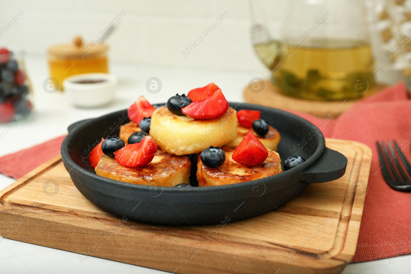 Photo of Delicious cottage cheese pancakes with fresh berries and honey served on white table