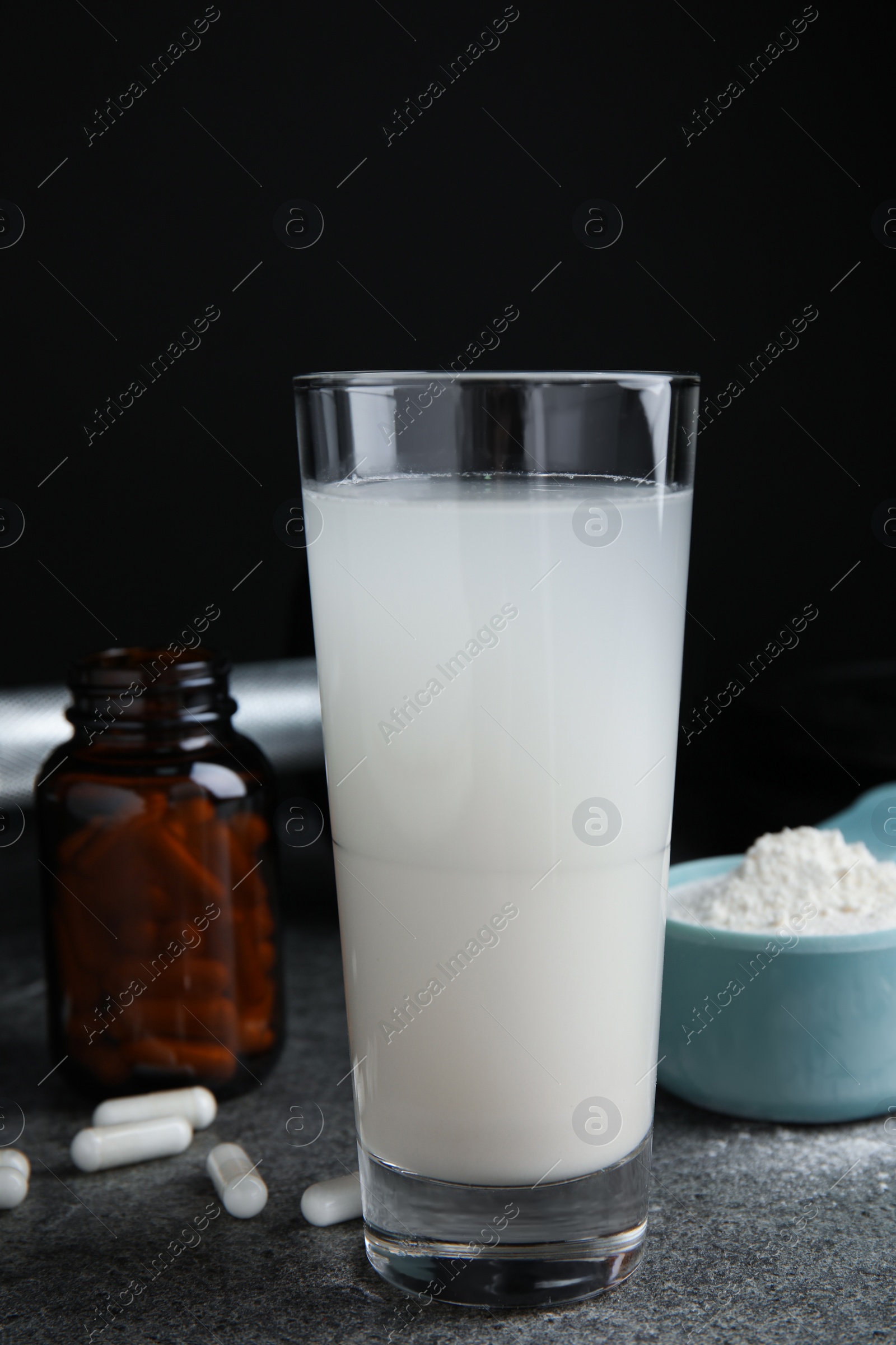 Photo of Amino acid shake, powder and pills on grey table