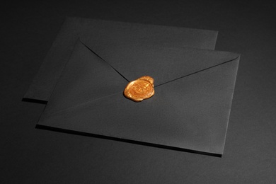 Photo of Envelopes with wax seal on black background