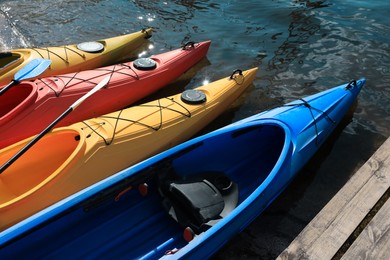 Photo of Modern kayaks with paddles on beach near river. Summer camp activity