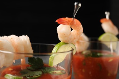 Tasty shrimp cocktail with sauce in glasses and lime on black background, closeup