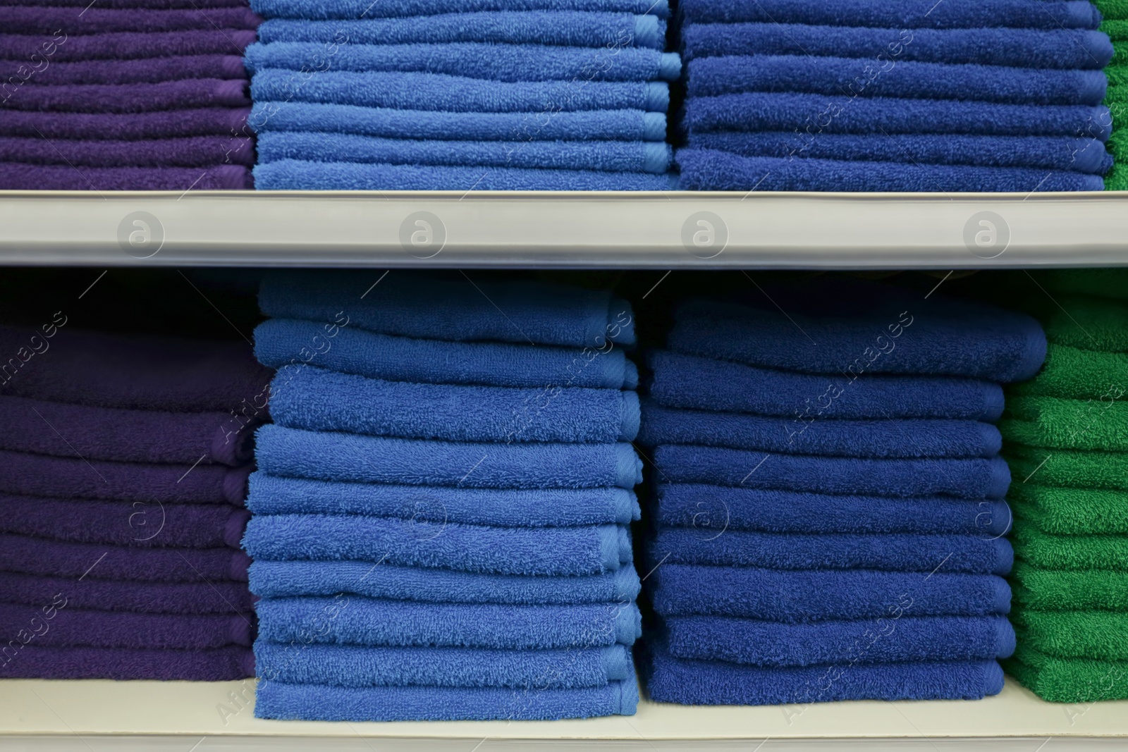 Photo of Stacks of colourful towels on store shelves