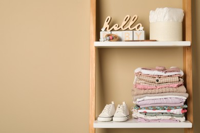 Photo of Baby clothes and accessories on wooden rack, space for text