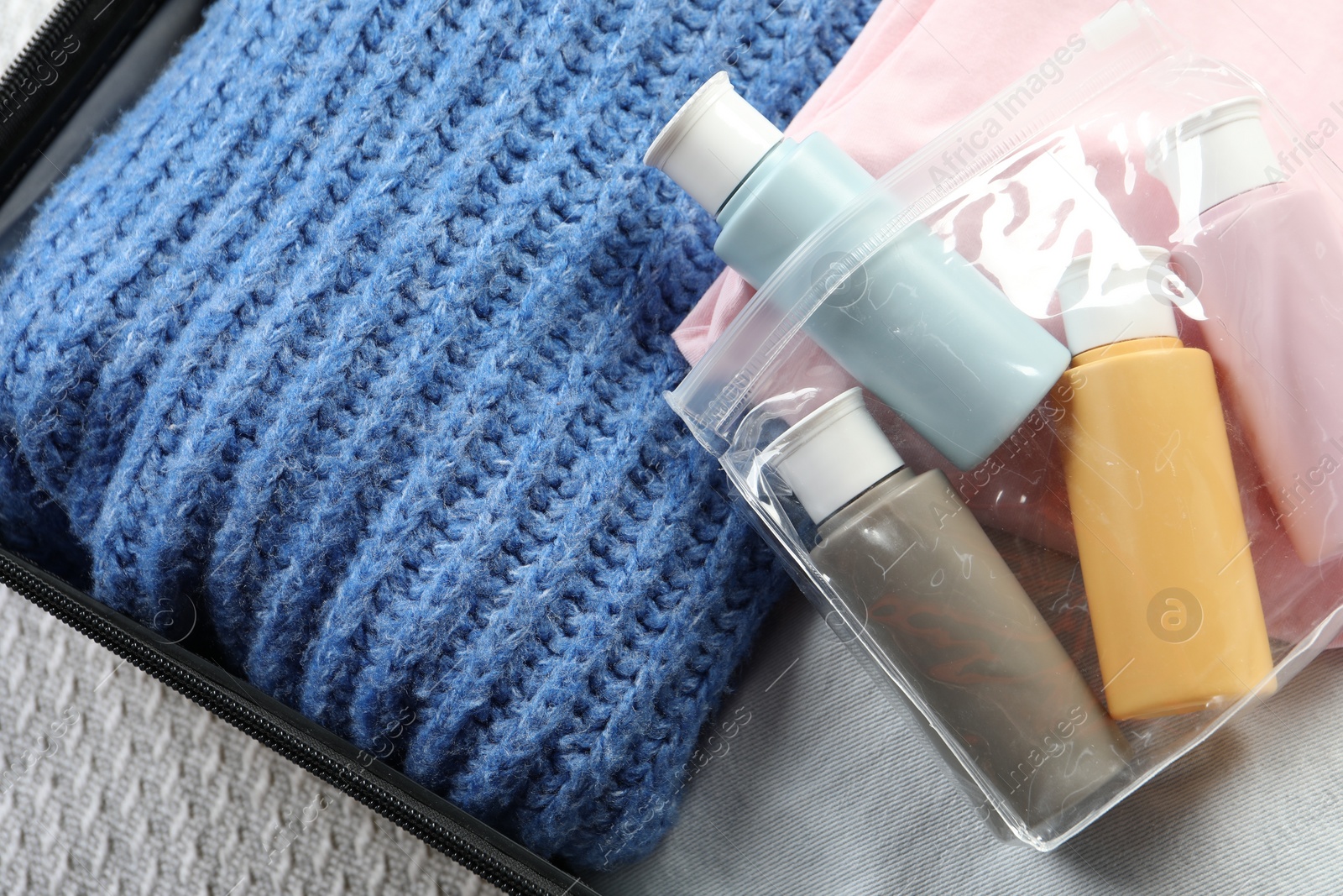 Photo of Plastic bag of cosmetic travel kit in suitcase, top view