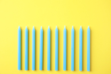 Blue birthday candles on yellow background, top view