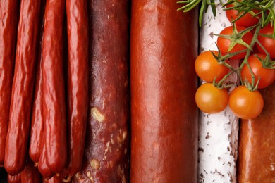 Photo of Different types of tasty sausages and tomatoes as background, top view