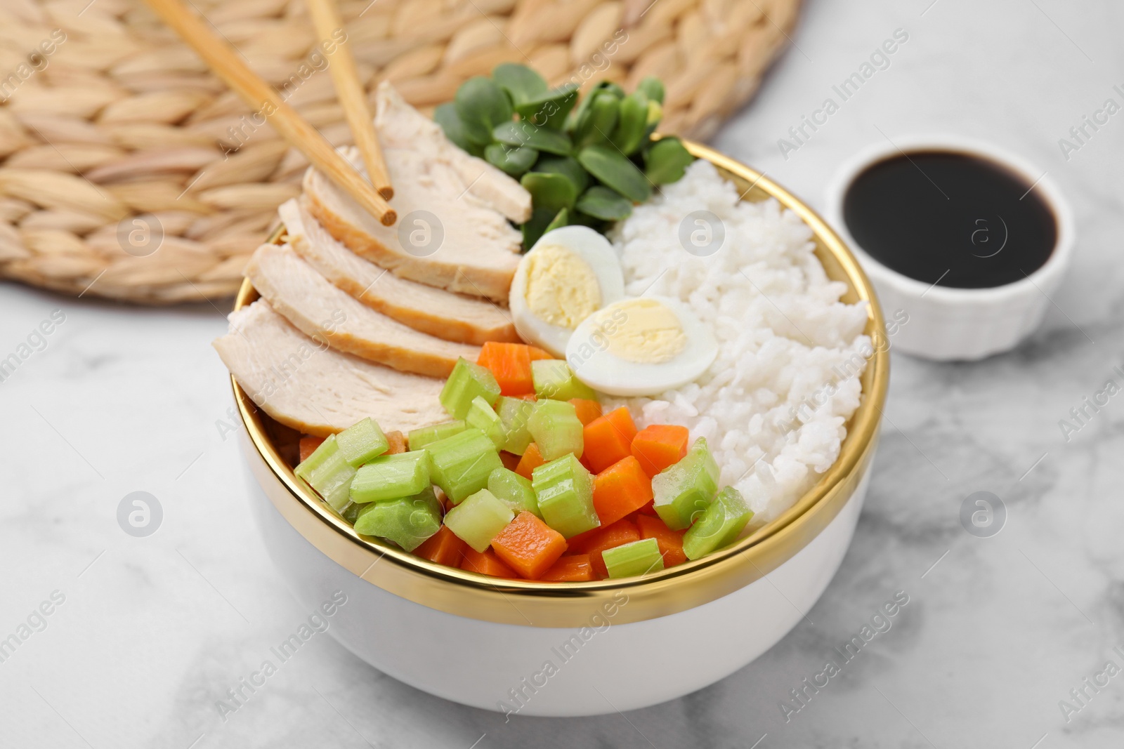 Photo of Delicious poke bowl with meat, rice, egg and vegetables served on white marble table, closeup