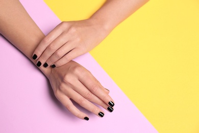 Photo of Woman with black manicure on color background, top view and space for text. Nail polish trends