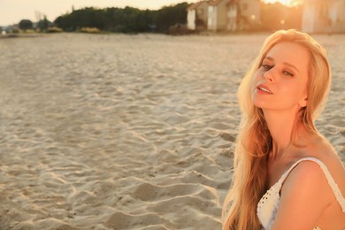 Photo of Beautiful young woman on sandy beach, space for text