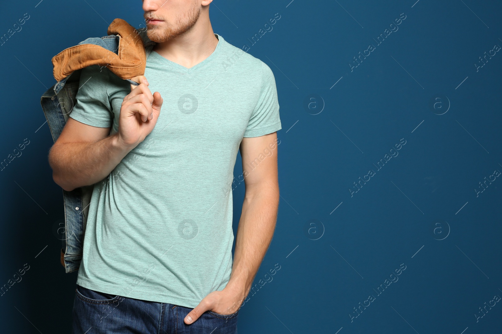 Photo of Young man wearing blank t-shirt on blue background, closeup. Mockup for design