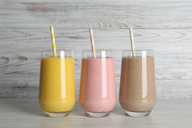 Photo of Glasses with different smoothies on white wooden table