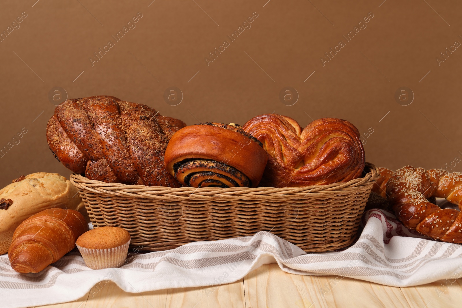 Photo of Wicker basket with different tasty freshly baked pastries on white wooden table