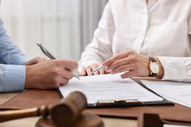 Photo of Lawyers working with documents at table in office, closeup